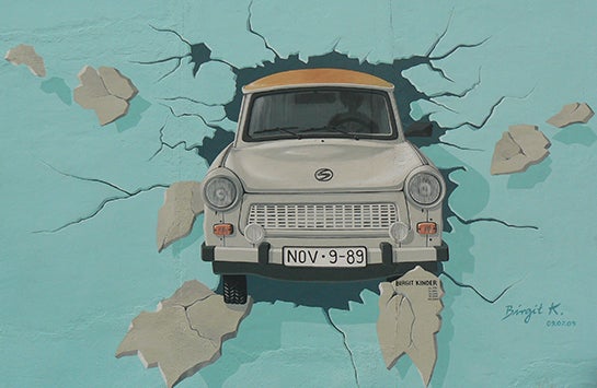 Graffiti of a car crashing through a wall. Painted on the Berlin Wall.