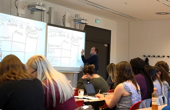 a male professor does German grammar exercises in front of a class of female students in Vienna