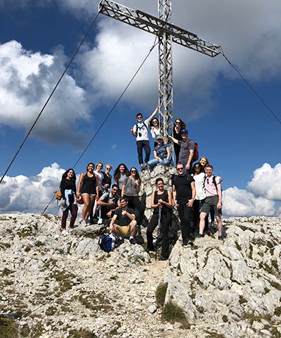 a mixed group of students stand atop a rocky hill