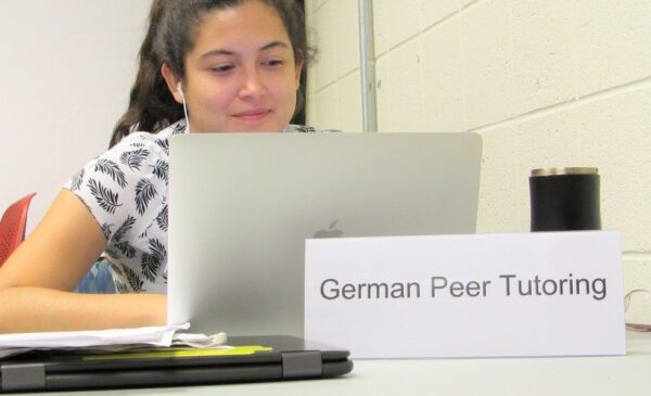 tutor on a laptop with a German Peer Tutoring sign